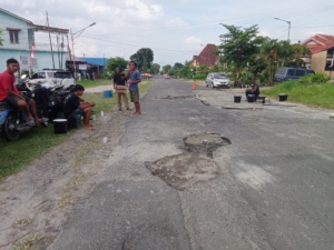Sejumlah pemuda lapangan bola atas kota Pematangsiantar melakuka perbaikan jalan secara swadaya.(Hegi)